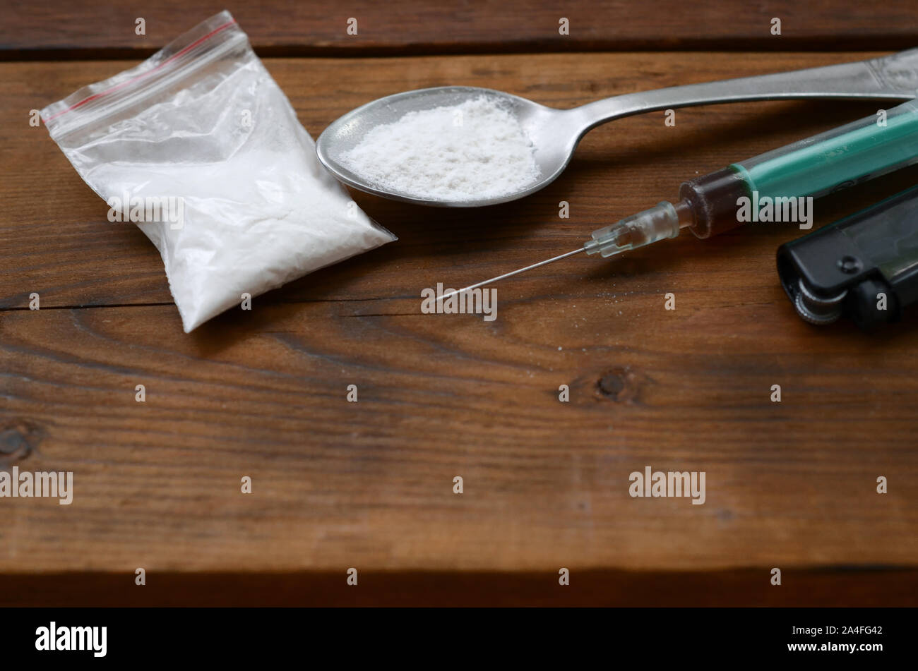 Drug dealer stuff. Syringe, lighter and spoon full of white powder on wooden background. Heroin and methamphetamine using. Narcotic addiction concept Stock Photo