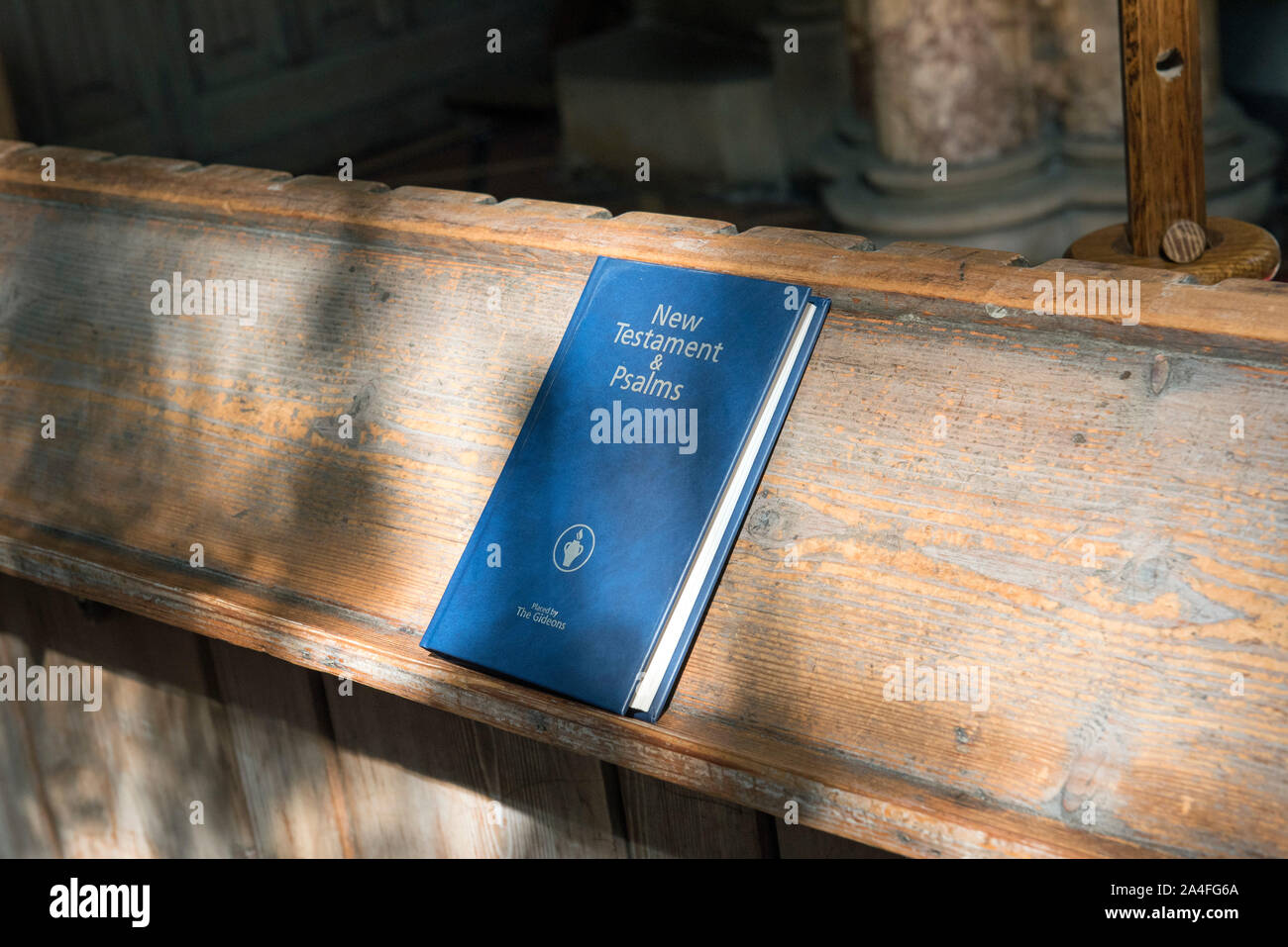 New Testament & Psalms book on back of pew in dappled sunlight with placed by The Gideons printed on the front Stock Photo