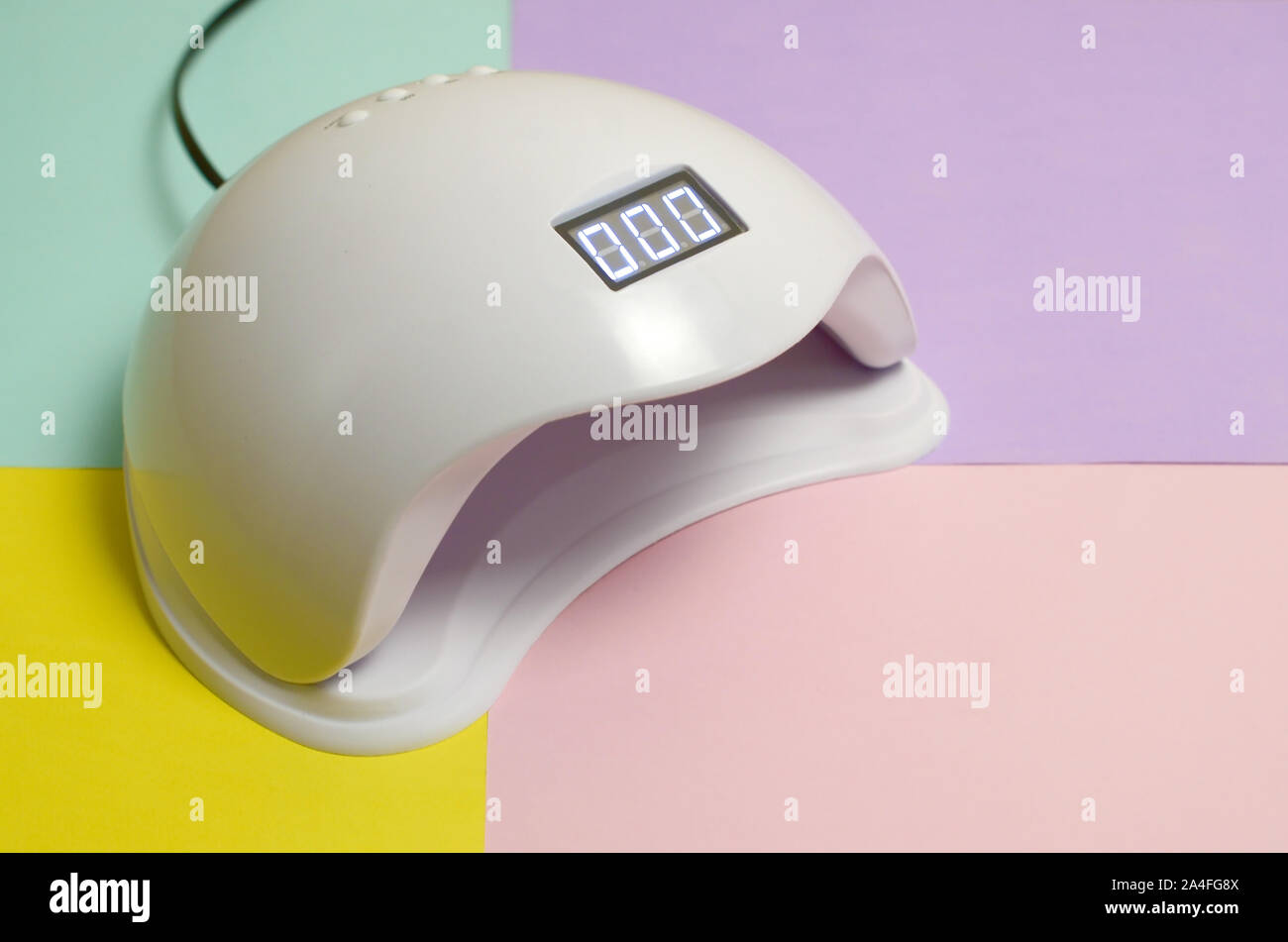 UV LED nail lamp for curing process by gel method lies on pastel multi