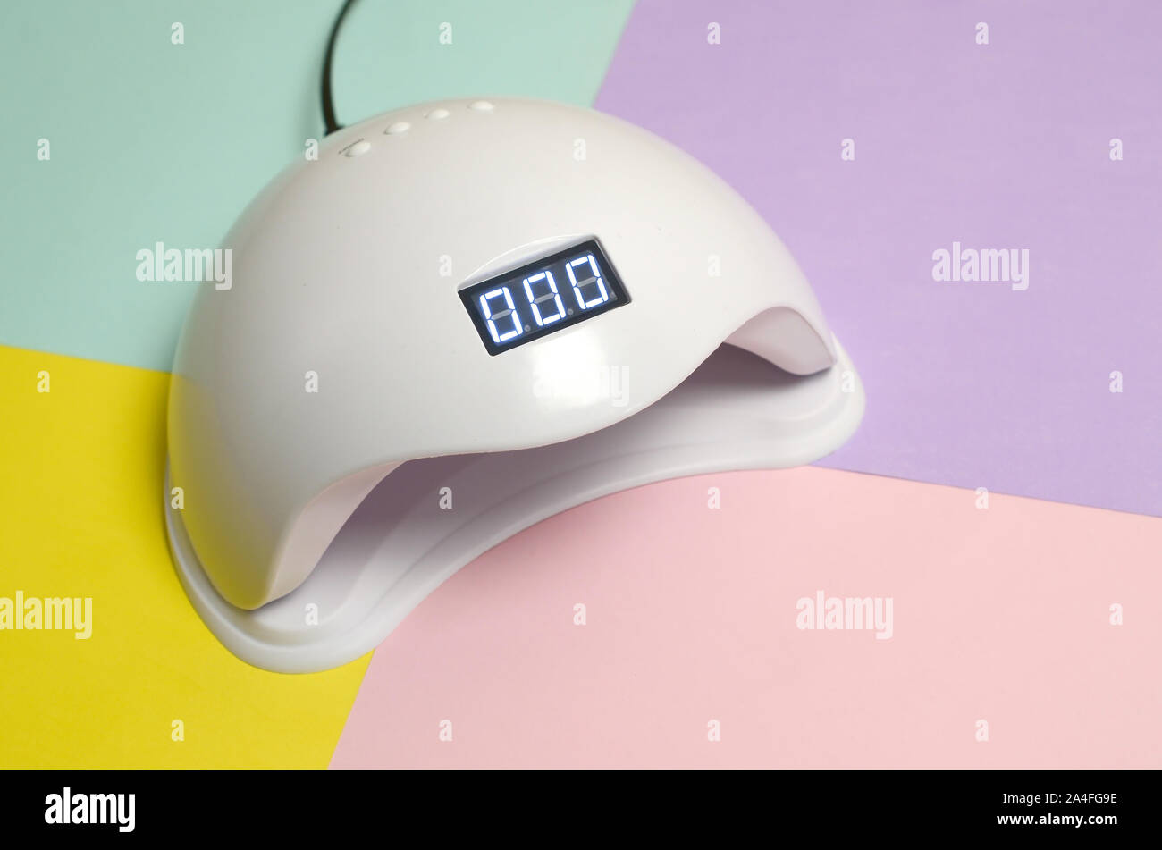 UV LED nail lamp for curing process by gel method lies on pastel multi