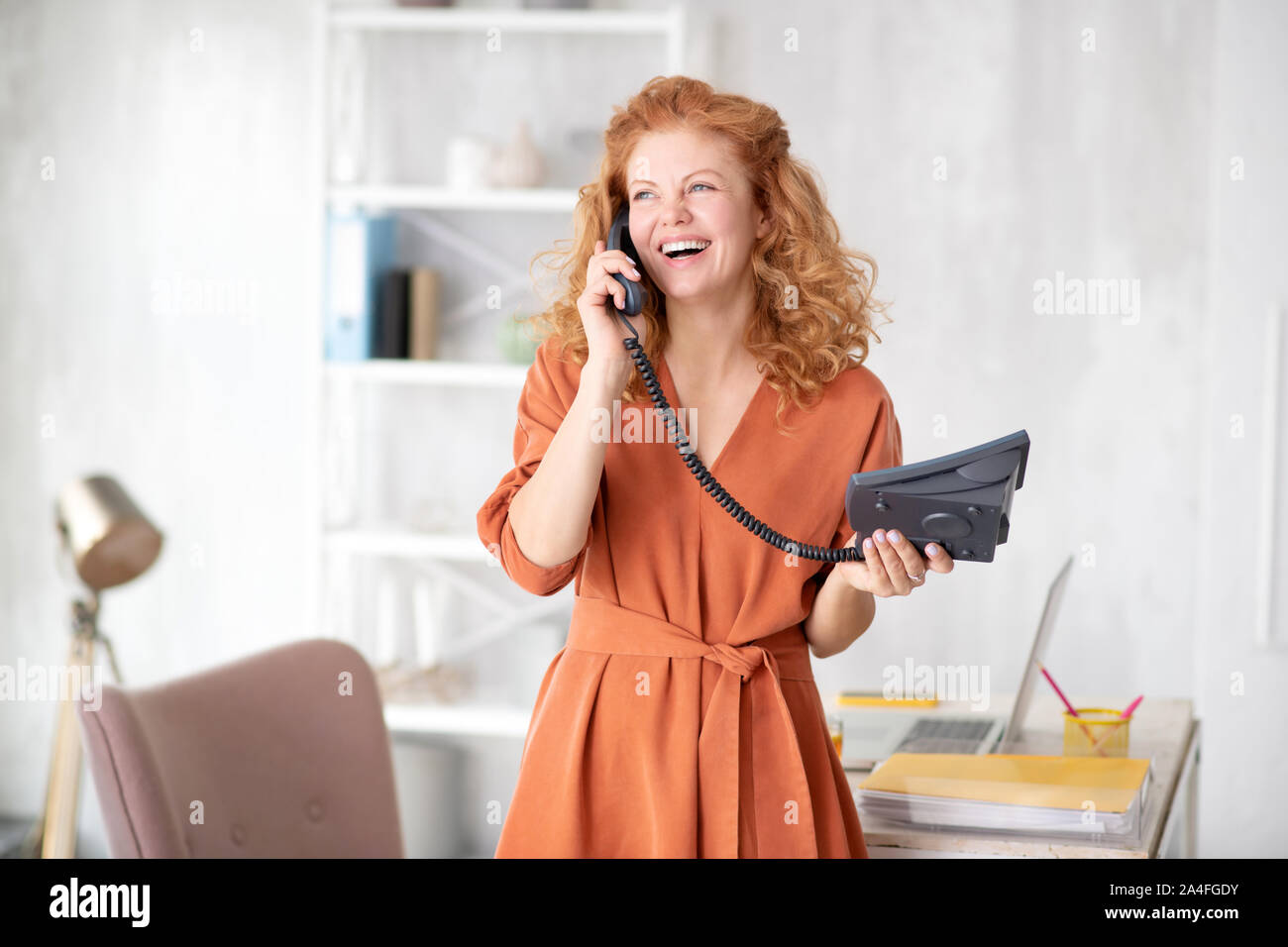 Cheerful office worker calling business partner while working Stock