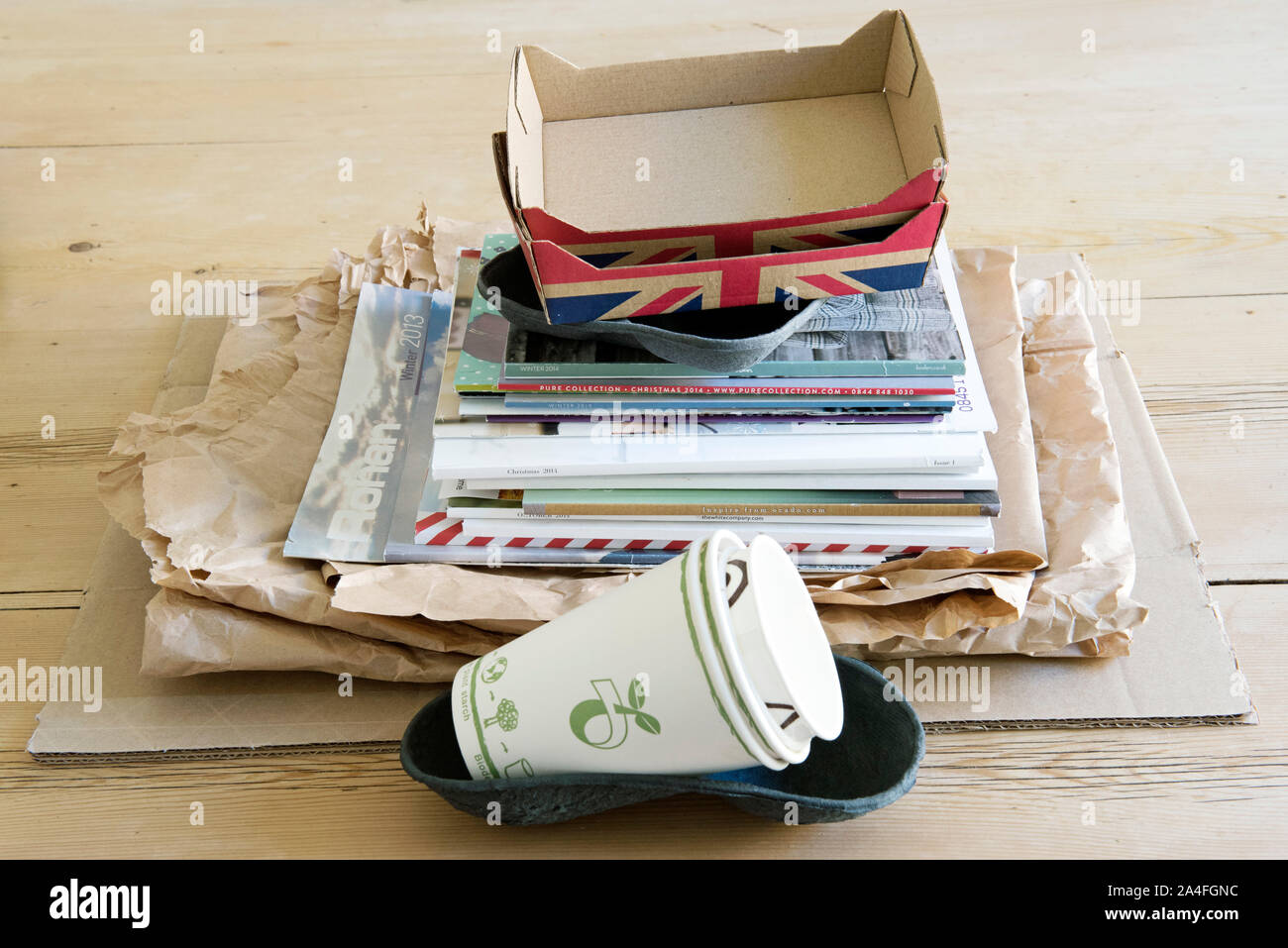 Recyclable Household items on kitchen table for recycling including, paper, cardboard fruit holders, mugs and old catalogues. Stock Photo