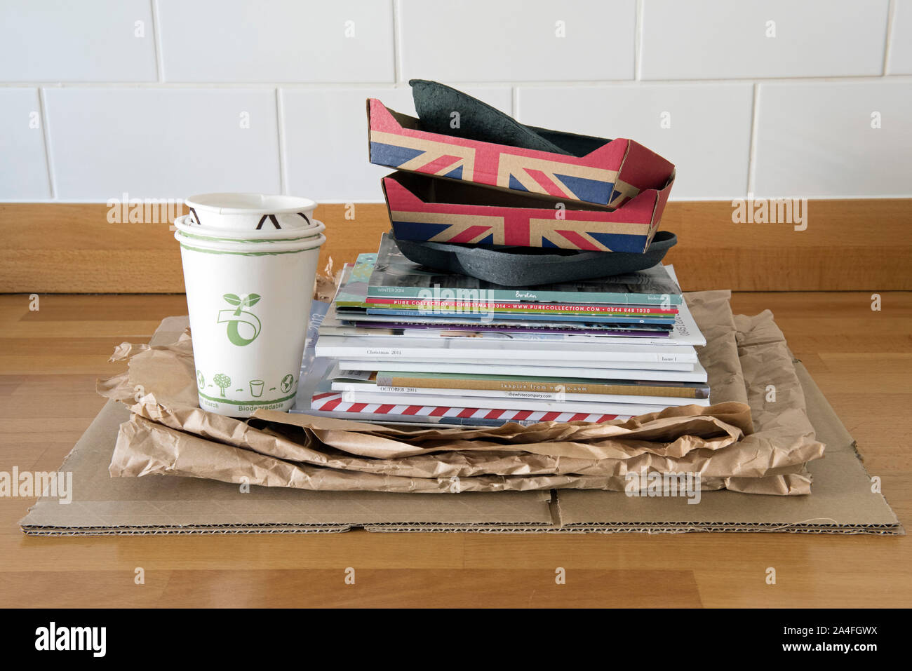 Recyclable Household items on kitchen worktop ready for recycling including, paper, cardboard fruit holders and old catalogues. Stock Photo