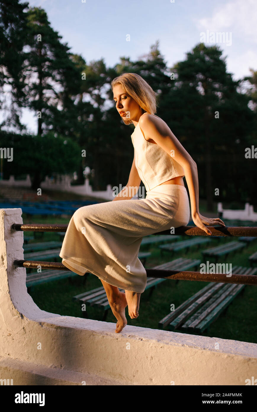 Woman sitting on a fence in a park Stock Photo