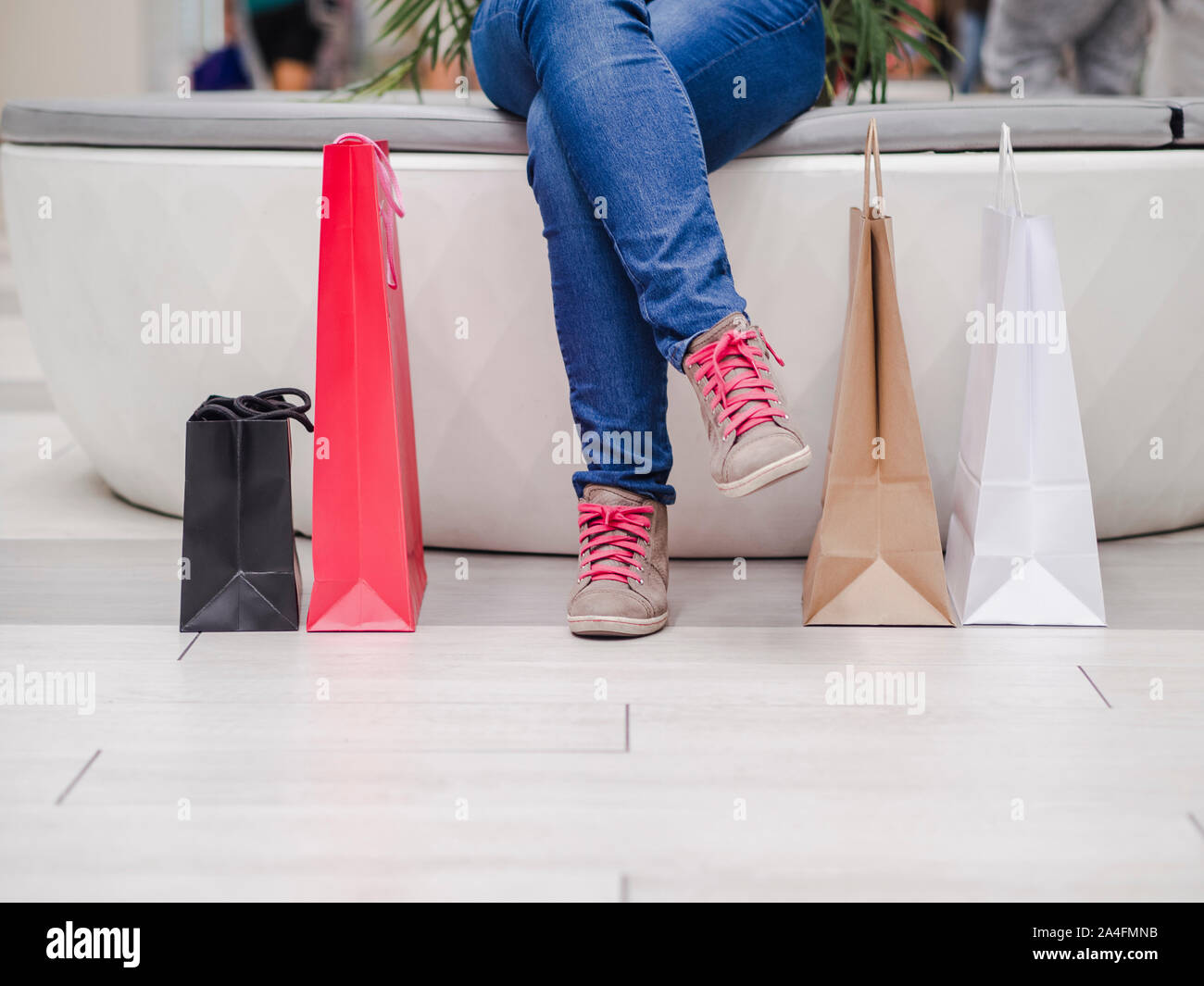 close up of a girl sitting with shopping bags in the mall. Shopping concept. Stock Photo