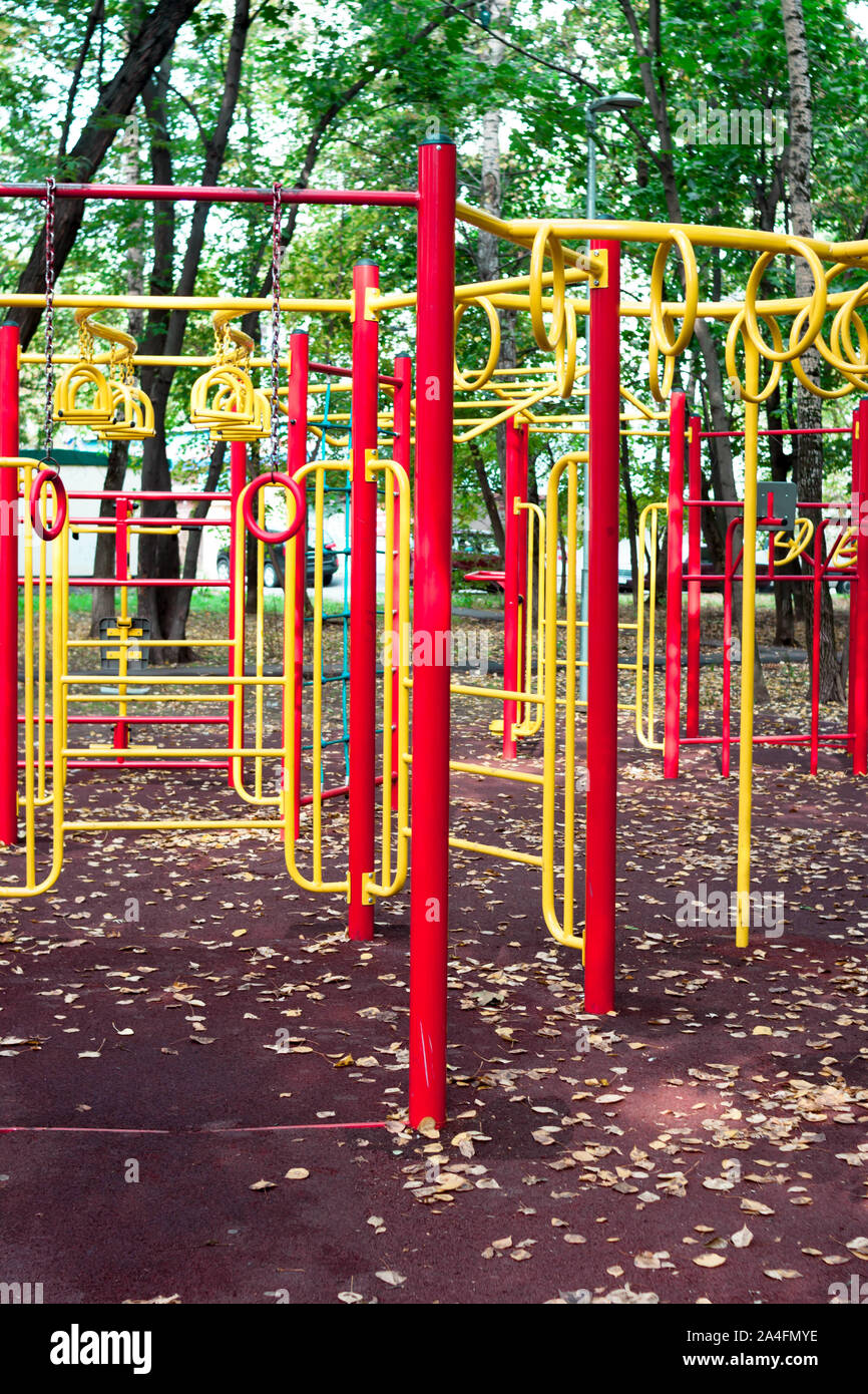 Metal children's outdoor playground equipment bars swing yellow and red color on natural background view. Stock Photo