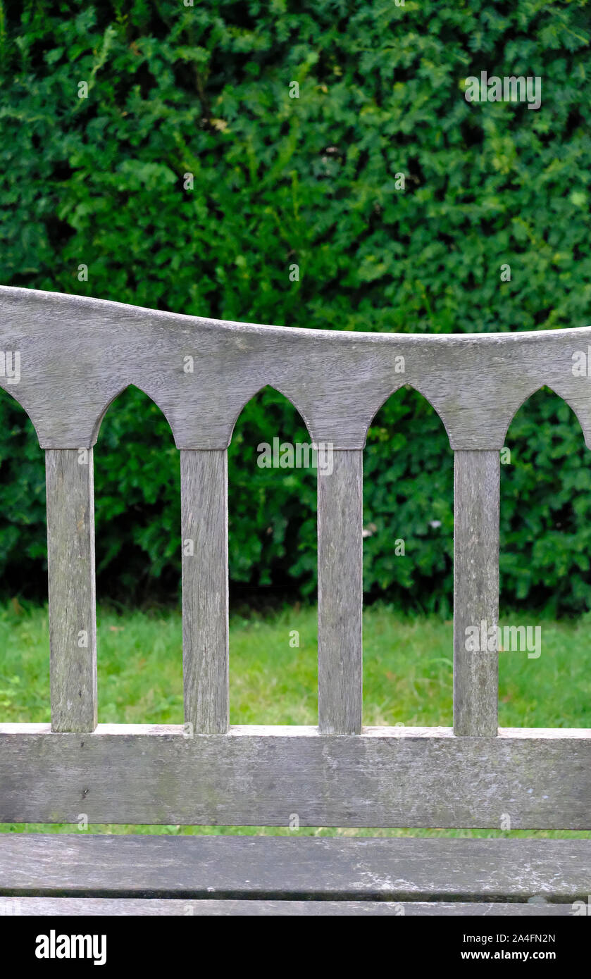 Gothic Arch detail from the back of a wooden garden seat in an English Garden Stock Photo