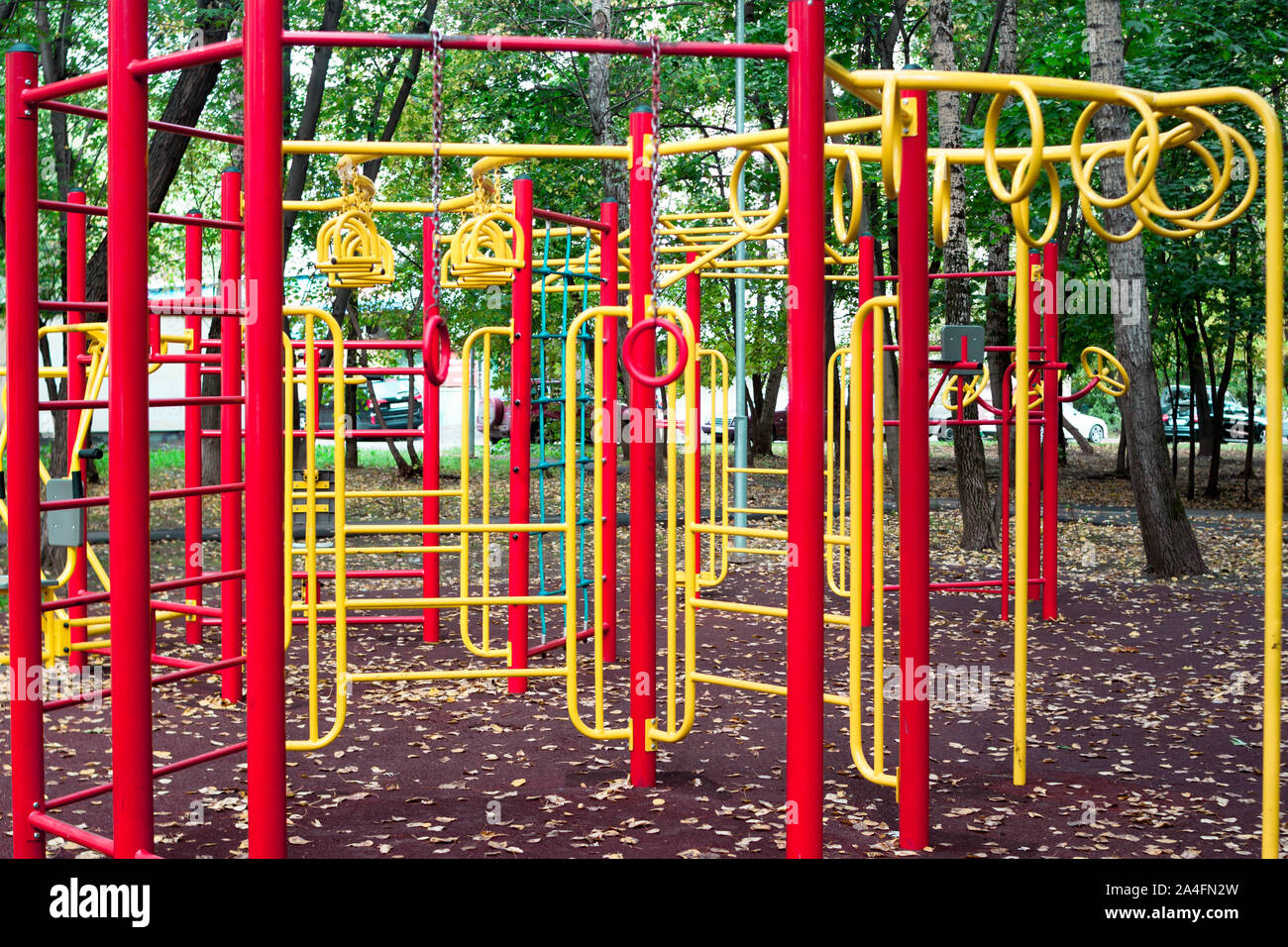 Metal children's outdoor playground equipment bars swing yellow and red color on natural background view. Stock Photo