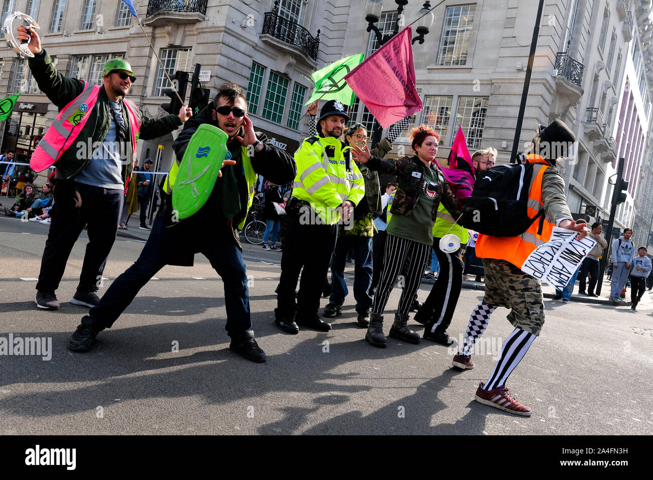 London, UK. Climate protesters with the Extinction Rebellion protest dance in front of a police officer at Piccadilly Circus. Stock Photo