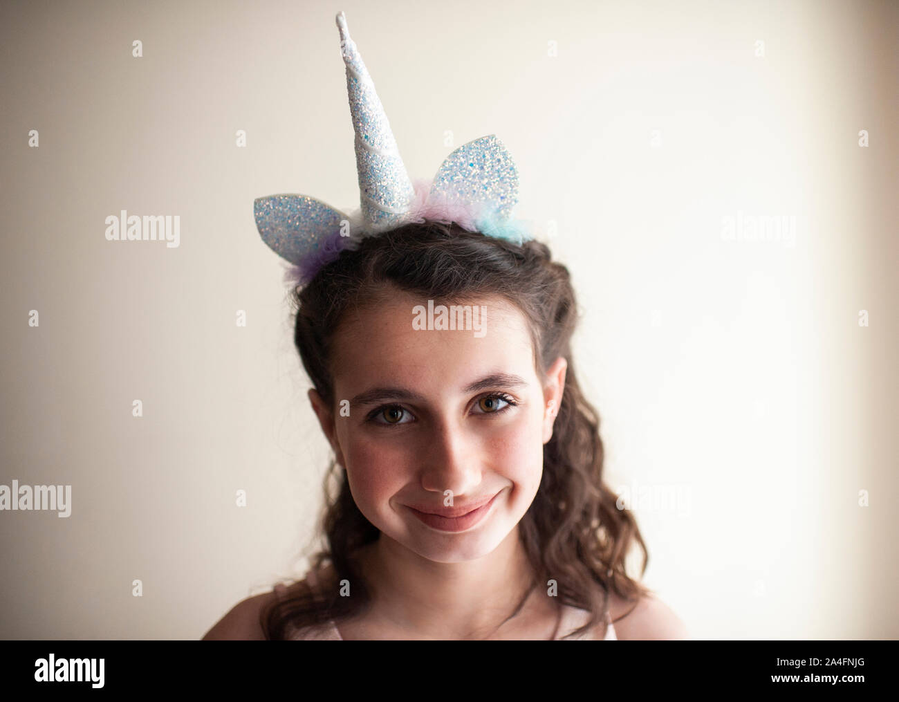Close up of girl 10-12 years old smiling with unicorn headband on Stock Photo