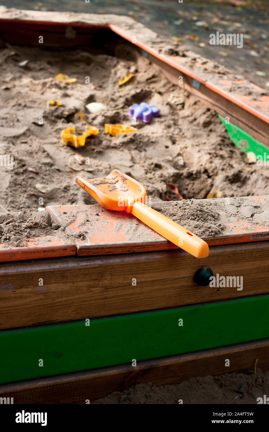 Plastic children toys molds scoop in sandpit with sand at kids playground. Side natural background view. Selective soft focus. Shallow depth of field. Stock Photo