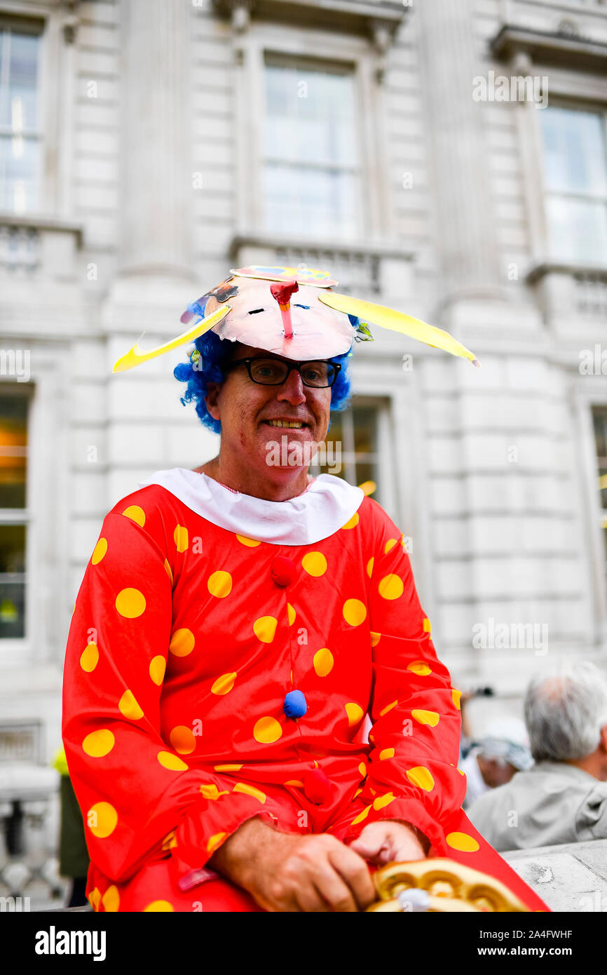 London, UK. A man in a clown suit and a Boris Johnson mask sits on a wall outside the Cabinet Offices in Whitehall. Stock Photo