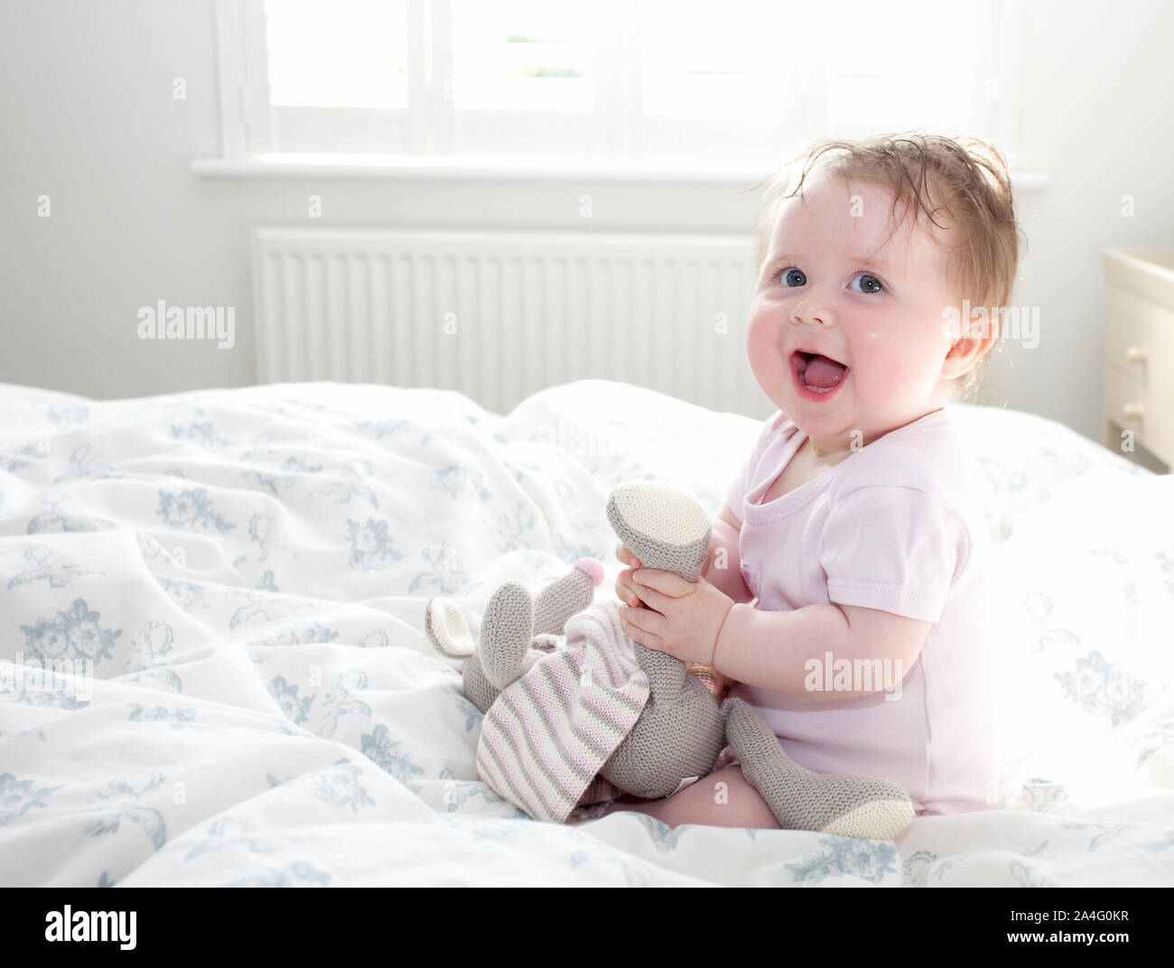 Baby sat on bed smiling for camera Stock Photo