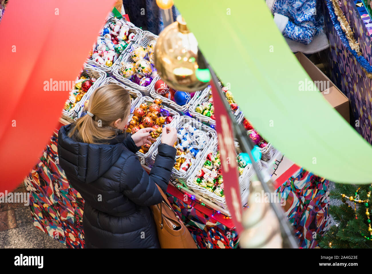 RUSSIA - MOSCOW. 28.12.2018. Christmas market in GUM. Young woman buys souvenirs to Christmas tree. View from above. Stock Photo