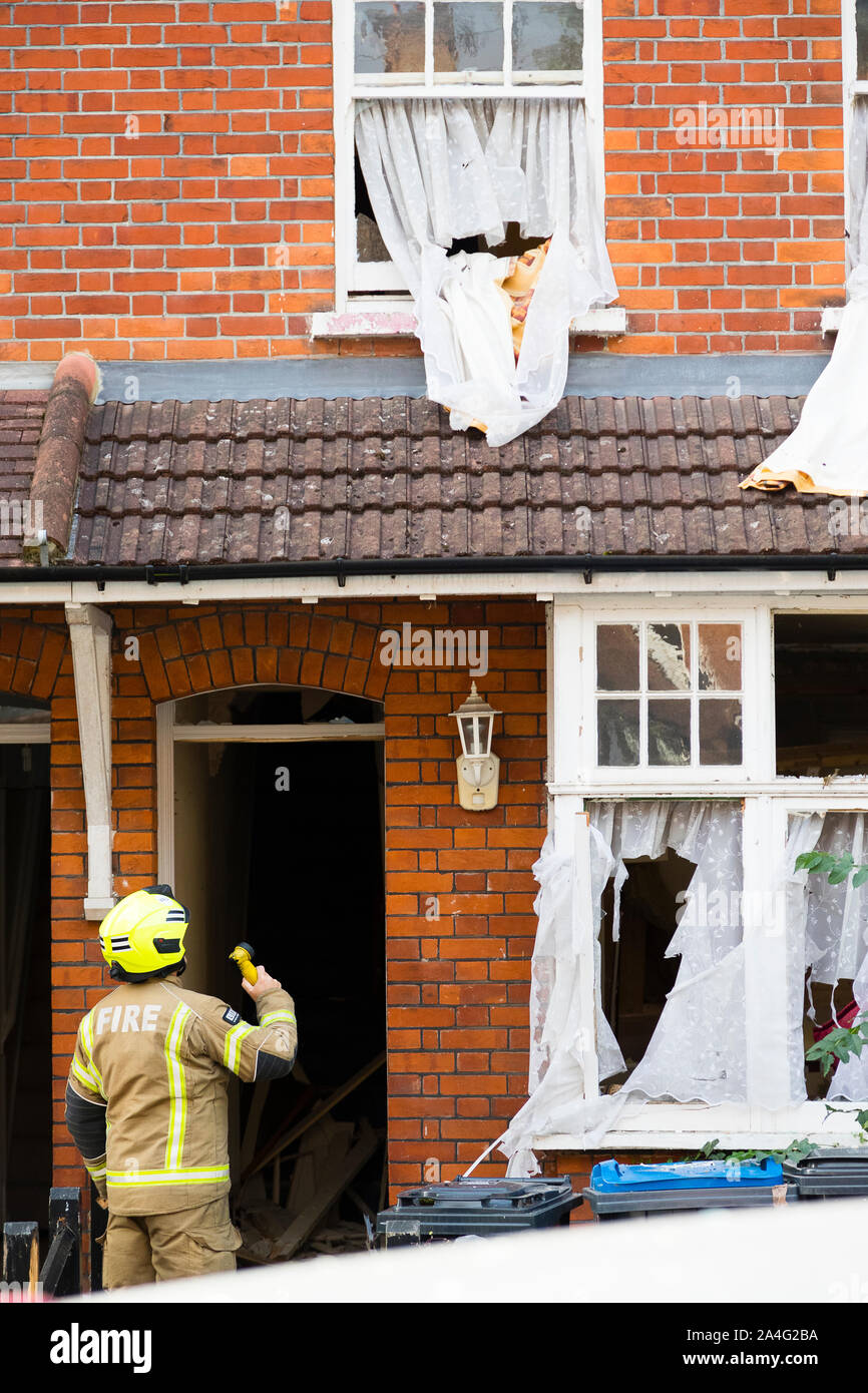 A firefighter shines a torch into a terraced house extensively damaged in a large gas explosion minutes before on Foxley Gardens, a residential street Stock Photo