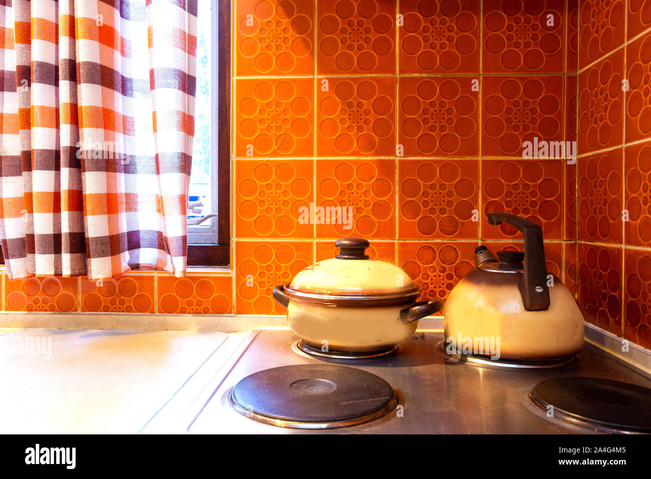 Original vintage kitchen of middle class with orange tiles and old stove with kitchen tools pans Stock Photo