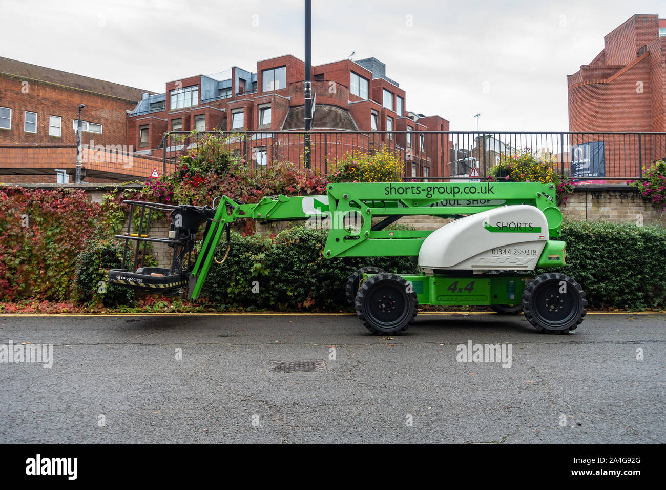 A green cherry picker parked at the side of a road. Stock Photo