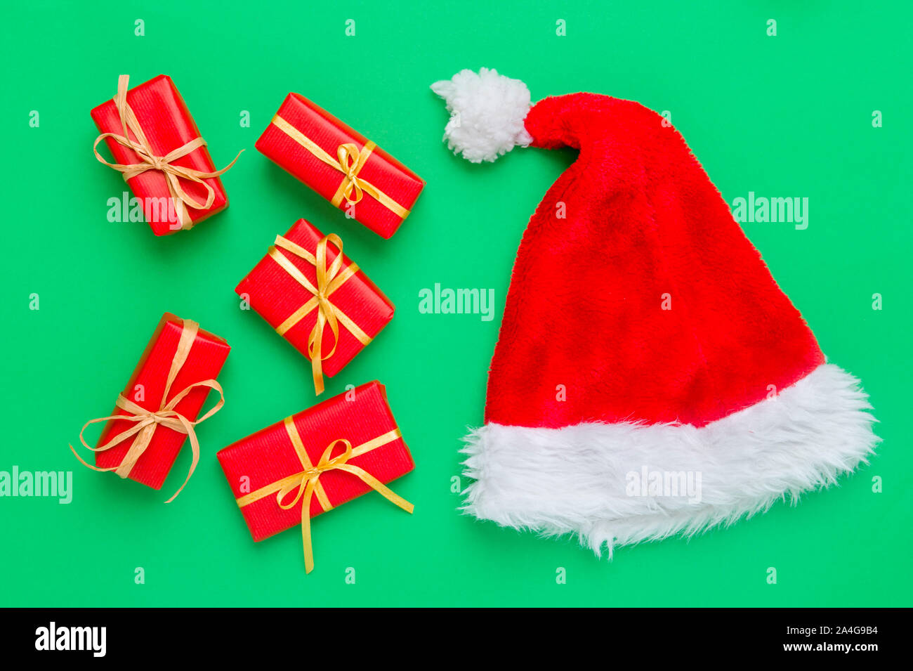 Gift boxes with santa hat on green background Stock Photo