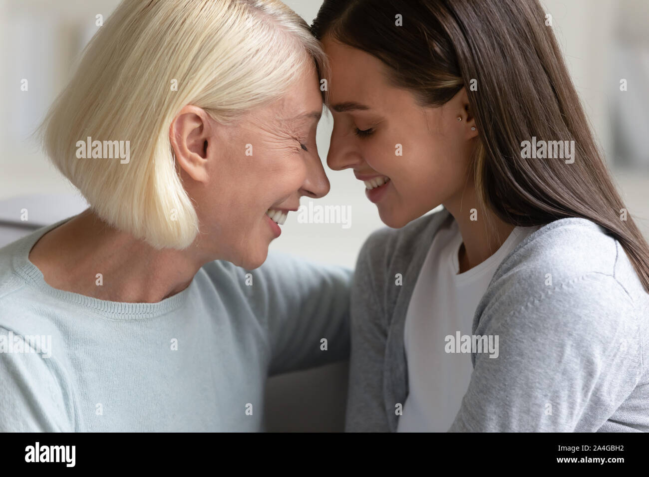 Happy elder woman touching foreheads with attractive daughter. Stock Photo