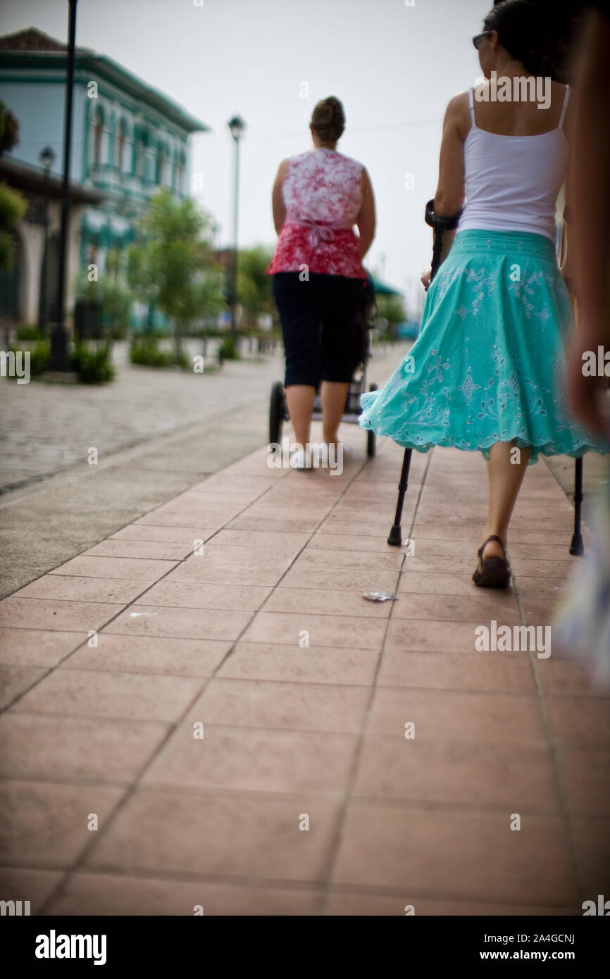 Woman with pushchair and woman with one leg walking along a sidewalk Stock  Photo - Alamy