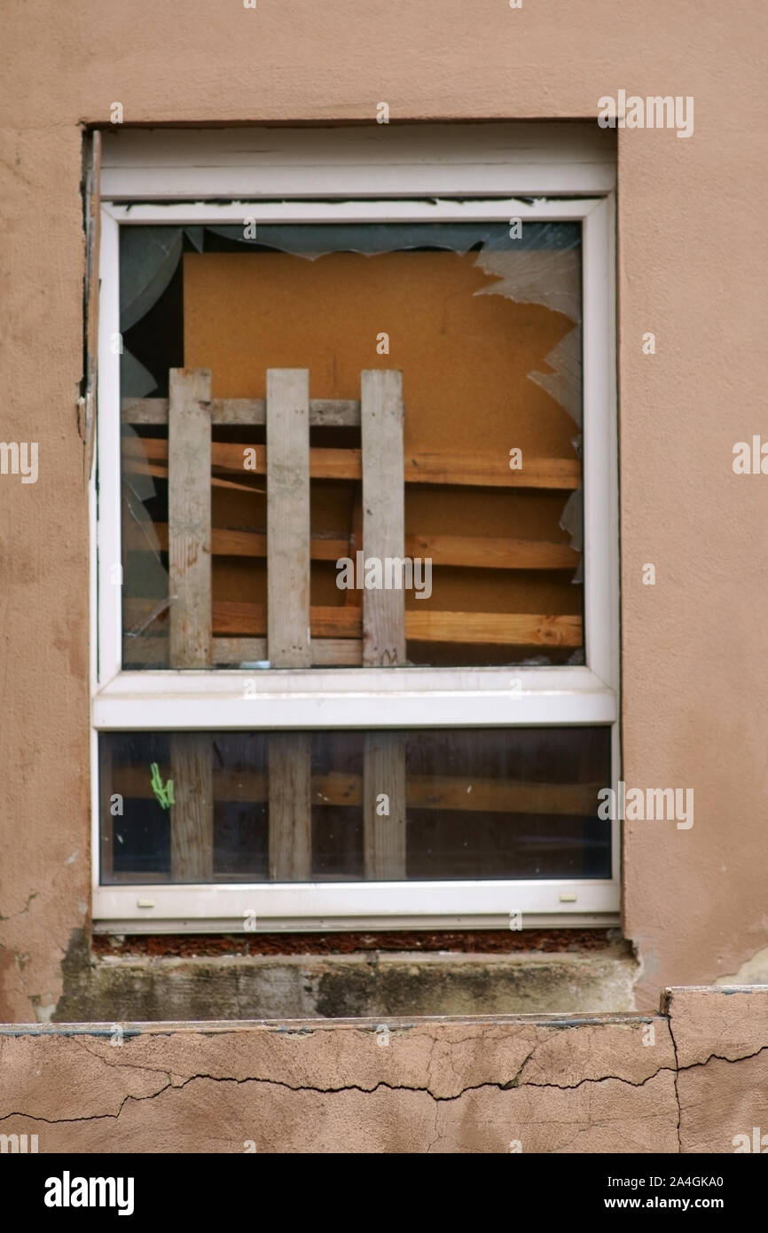 Bulky waste such as furniture and wood waste are behind a broken window. Stock Photo