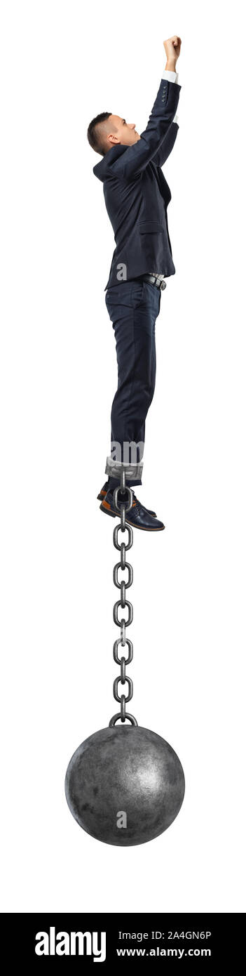 A businessman take a superhero jump in the air with an iron ball still attached to his ankle with a solid chain. Stock Photo