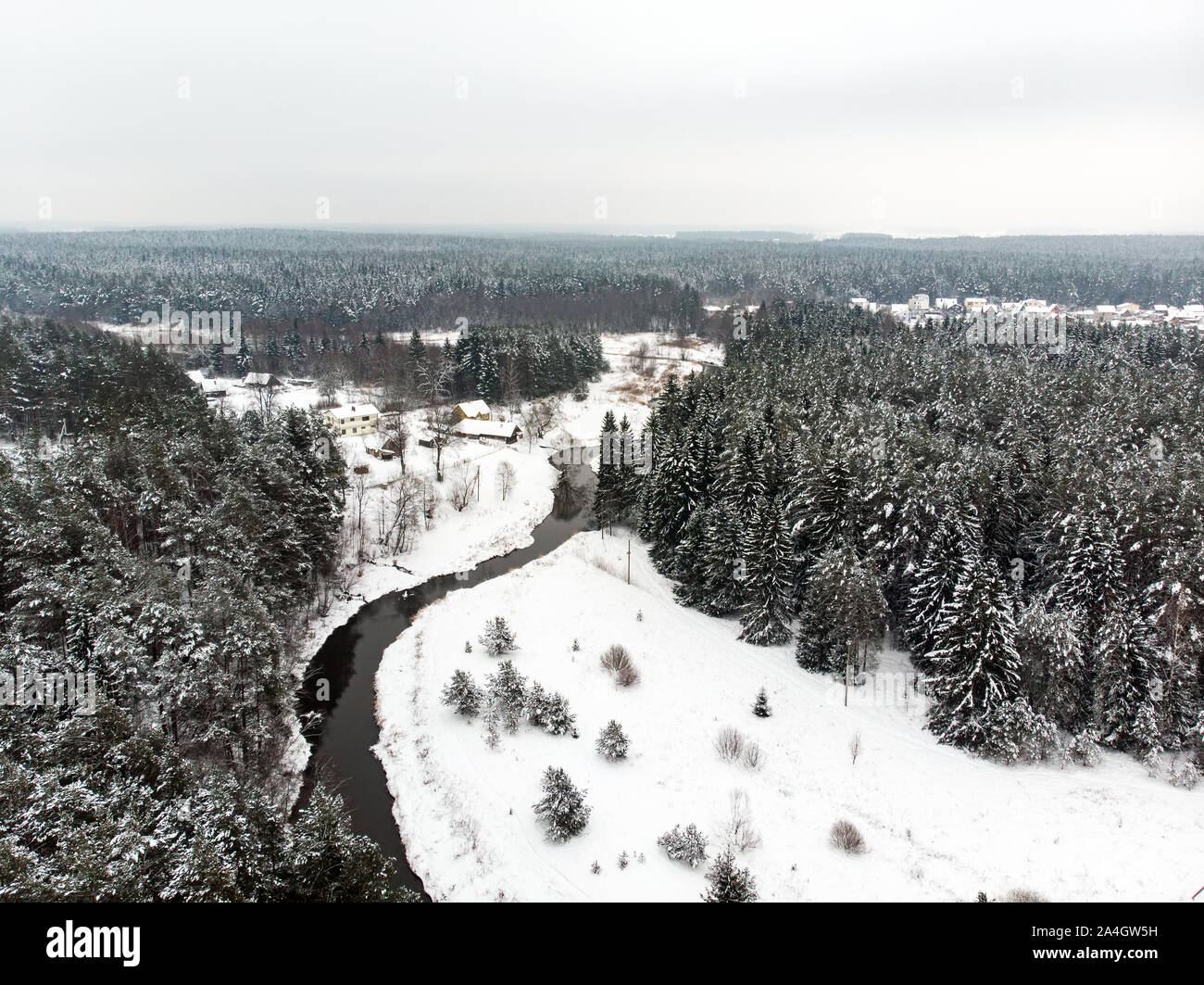 Beautiful aerial view of snow covered pine forests and a road winding ...