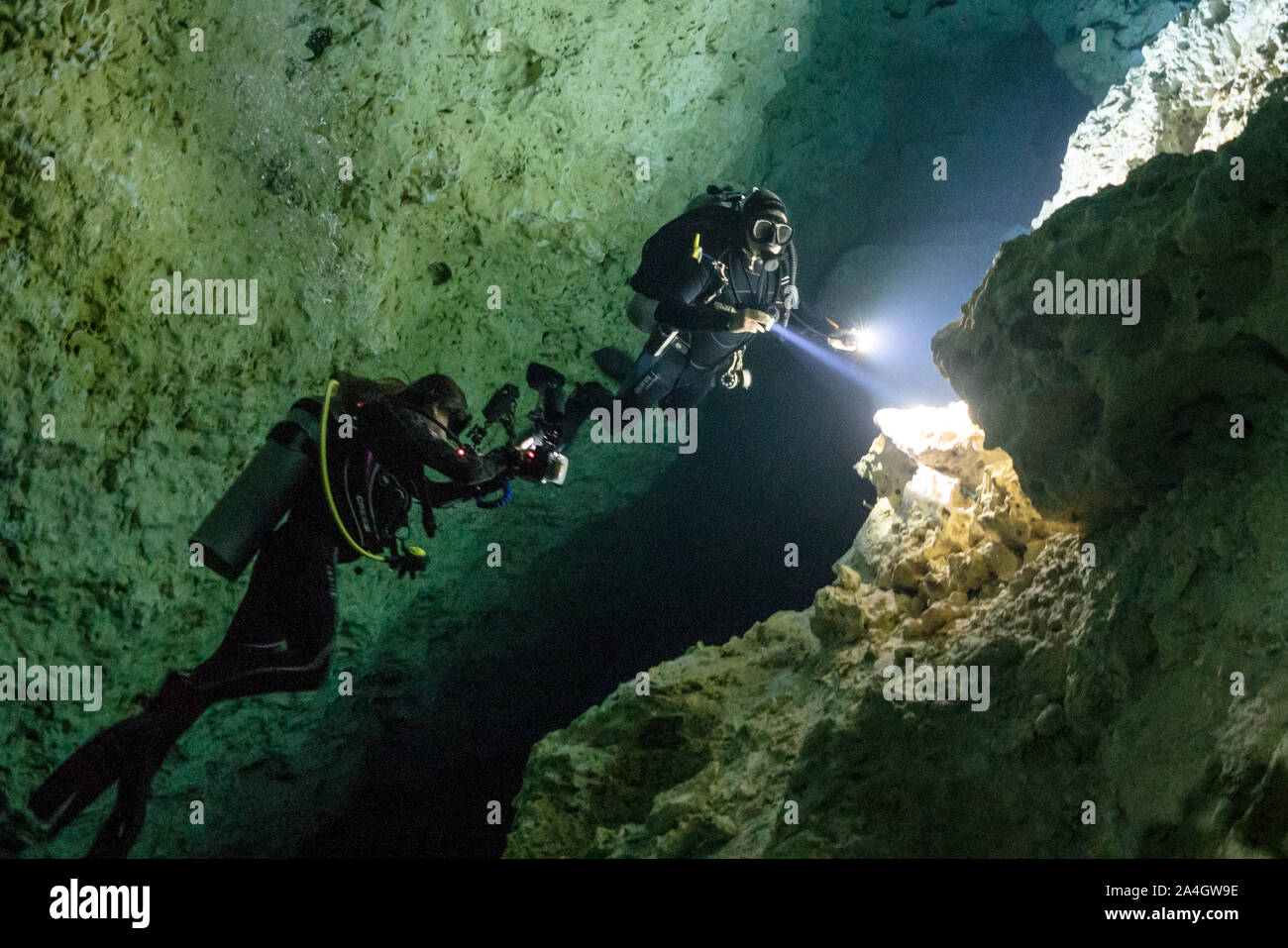 A dive guide helps an underwater photographer with an image in The Pit cenote. Stock Photo