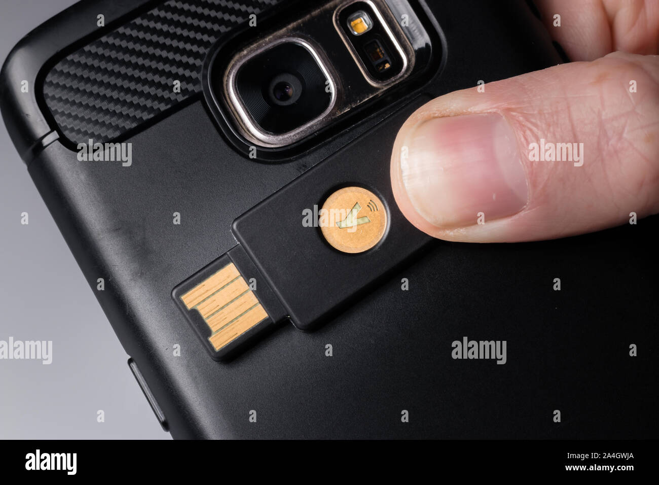 A Yubikey 5 security key using NFC to connect to a smartphone Stock Photo