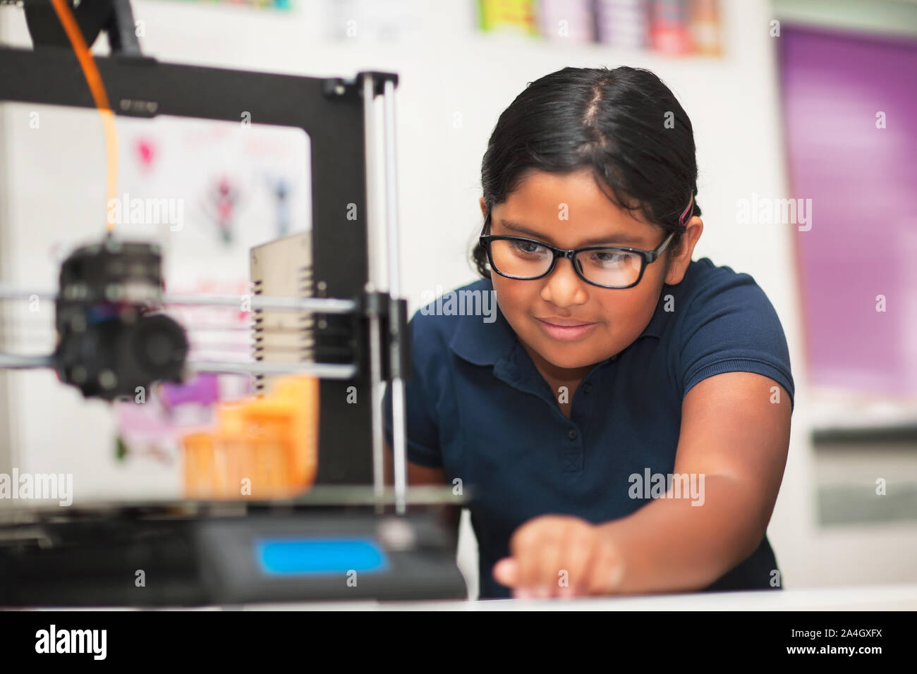 A female student in a modern classroom observing the printing process of a 3d model. Stock Photo