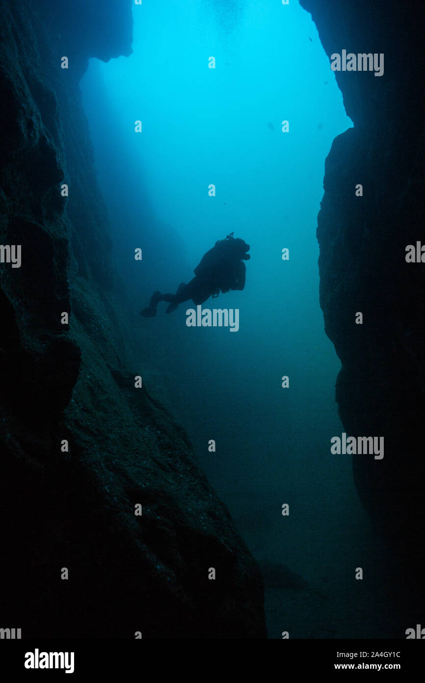 A scuba diver creates a striking silhouette from outside an underwater cave at Land's End in the Cabo San Lucas Marine Park, Mexico. Stock Photo