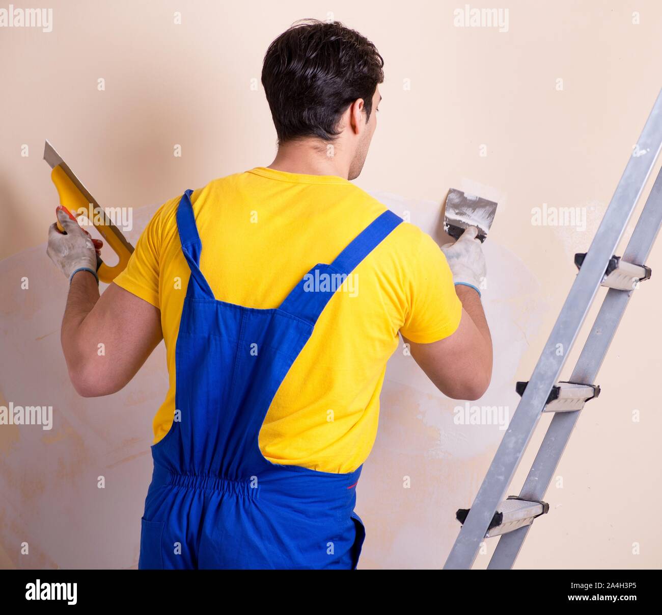 The young contractor employee applying plaster on wall Stock Photo