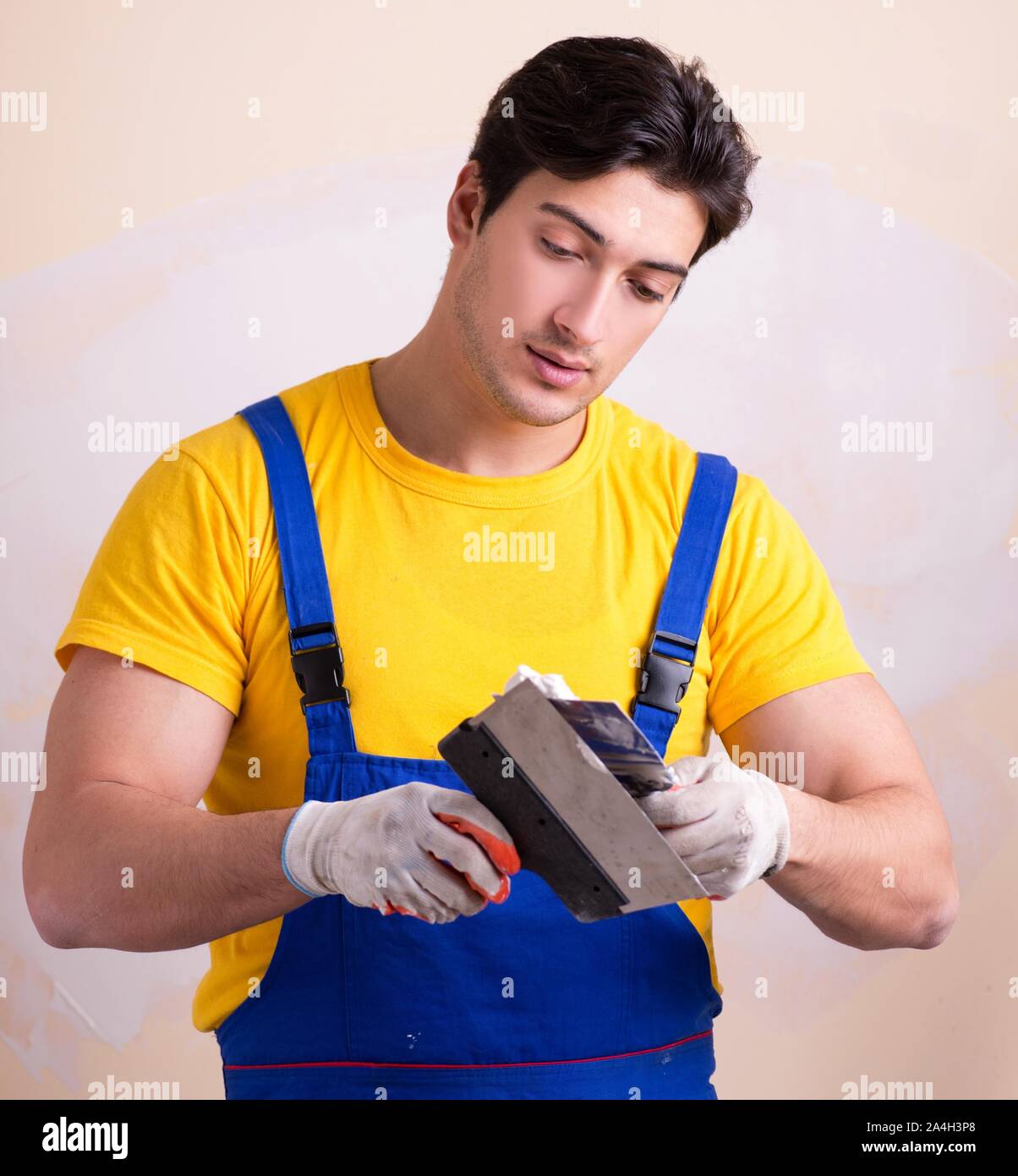 The young contractor employee applying plaster on wall Stock Photo