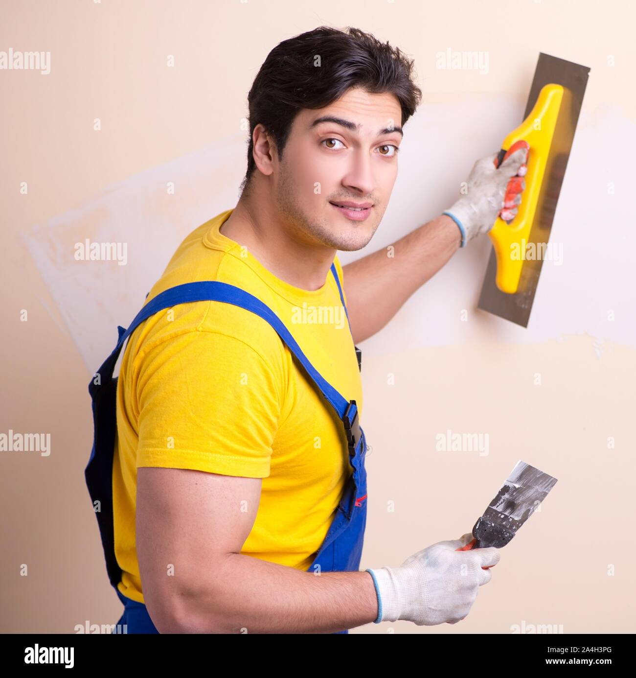 The young contractor employee applying plaster on wall Stock Photo