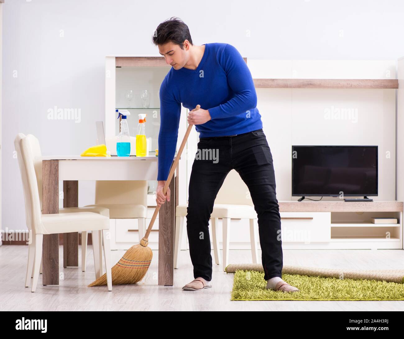 The young man cleaning floor with broom Stock Photo Alamy