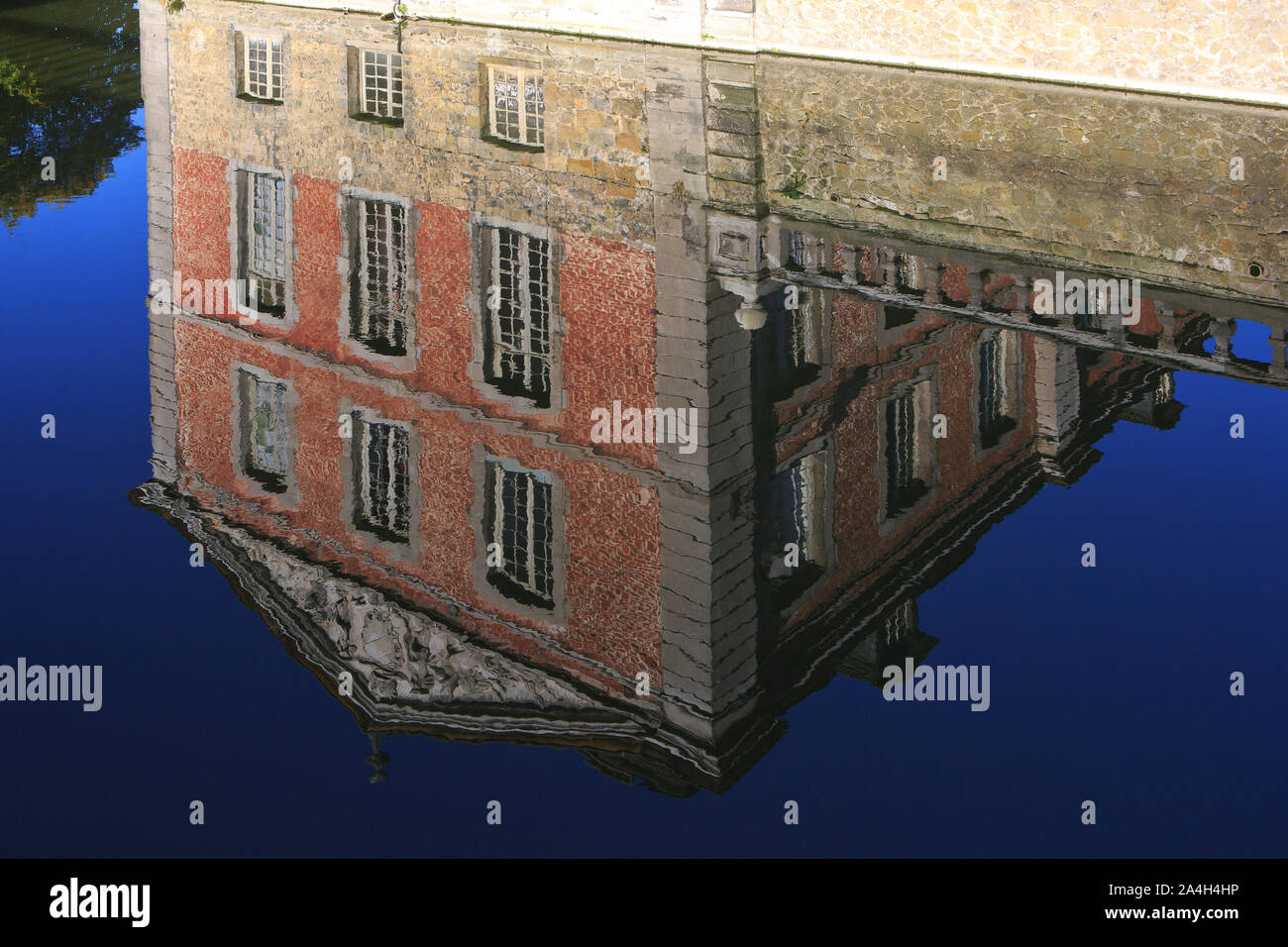 Reflection in the moat of the left wing with coat of arms at the Chateau de Beloeil, residence of the Prince de Ligne, in Beloeil (Hainaut), Belgium Stock Photo