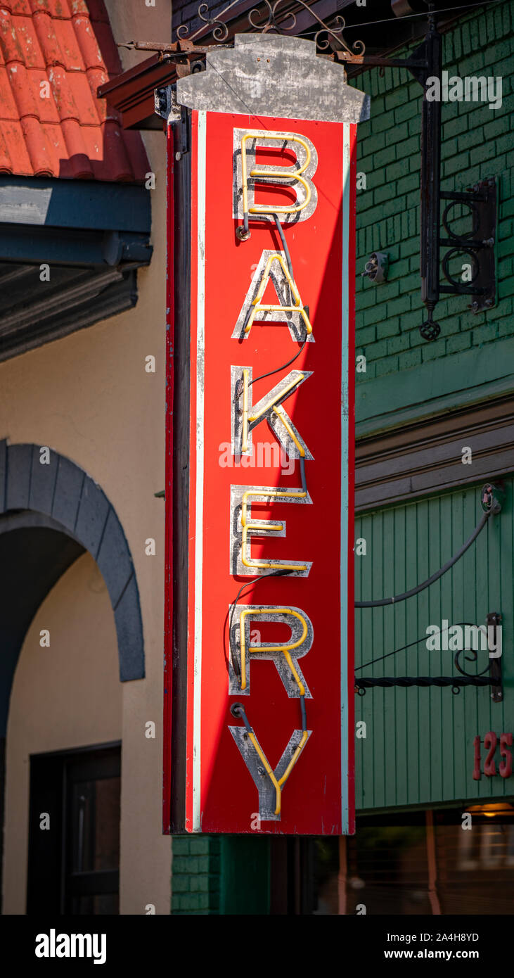 A red metal sign advertises a local downtown business that bakes food items Stock Photo