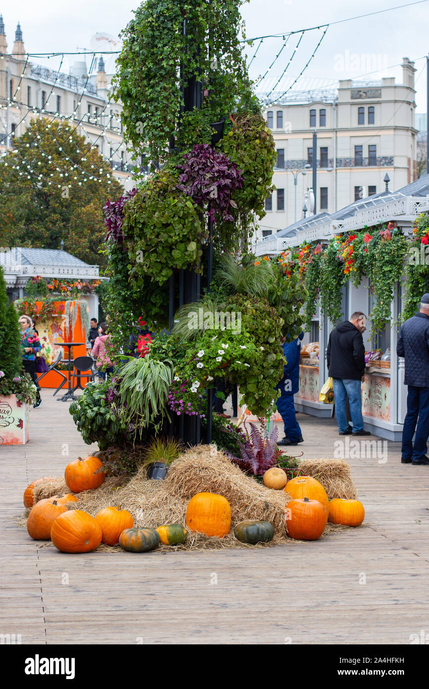 12-10-2019, Moscow, Russia. Golden Autumn festival. Vertical decoration of green plants and orange pumpkins. Holiday Kiosks with gifts and sweets Stock Photo