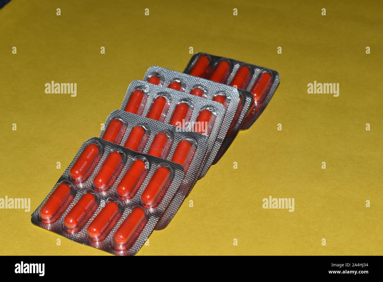 Red pill capsules in blister pack isolated on yellow background, in the