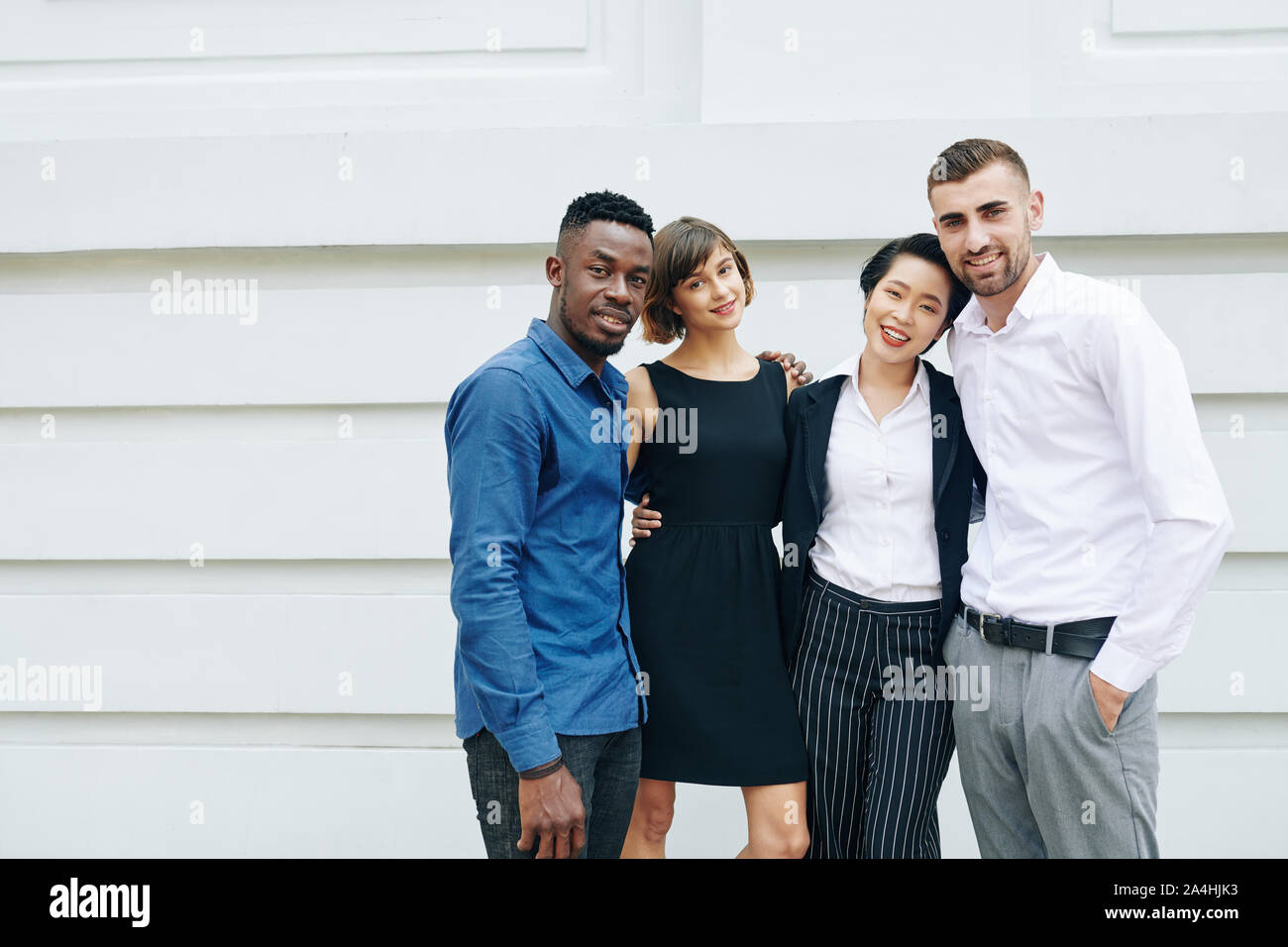 Group of happy hugging young business people standing outside the office building Stock Photo