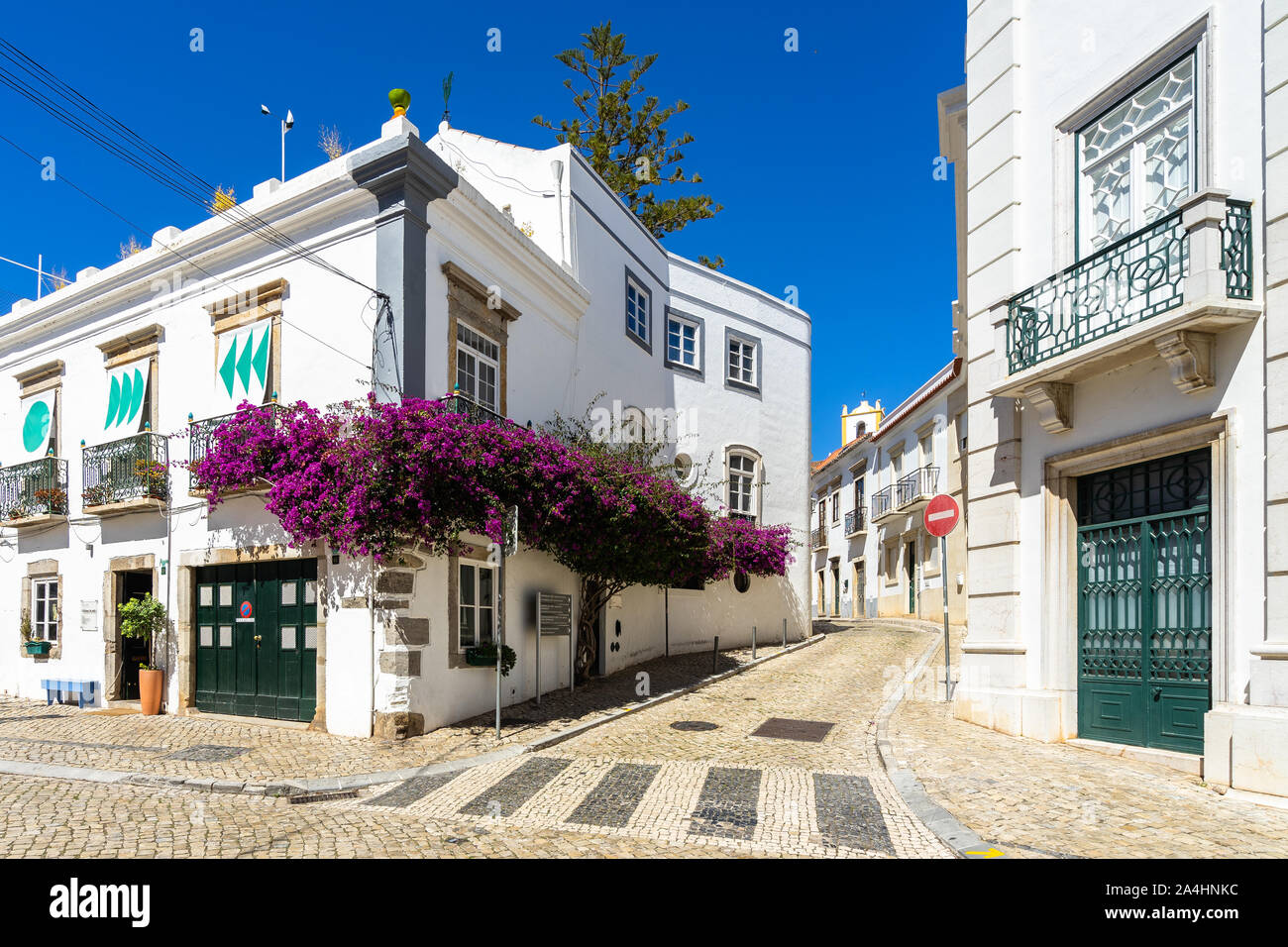 A picturesque street in Tavira with whitewashed houses decorated with bougainvillea flower,  Algarve, Portugal Stock Photo