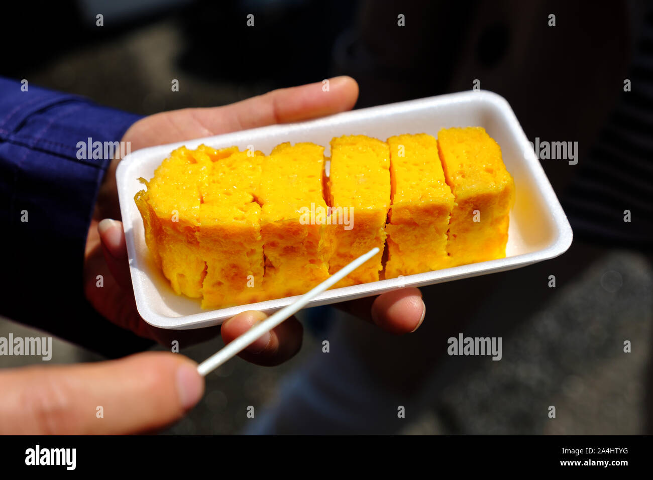 Closeup of women hands holding tamagoyaki Japanese eggs rolled omelet Stock Photo