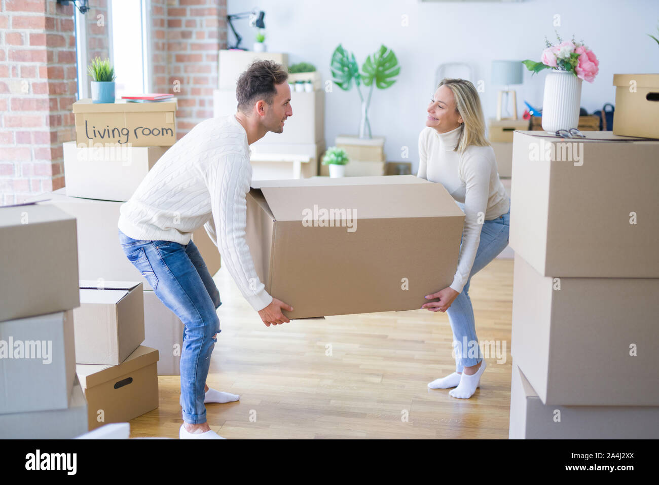 Young beautiful couple moving cardboard boxes at new home Stock Photo ...