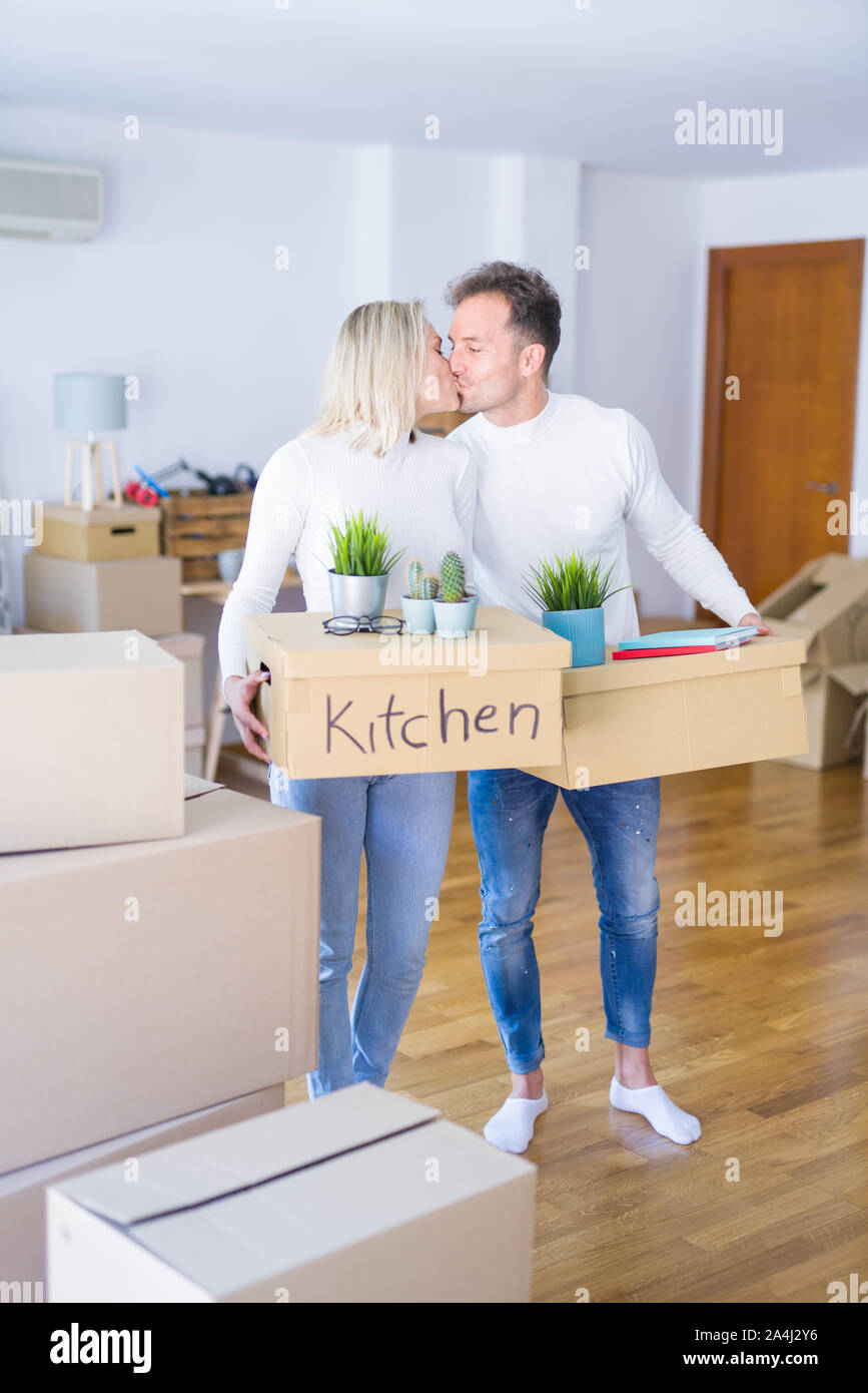 Young beautiful couple kissing moving cardboard boxes at new home Stock ...