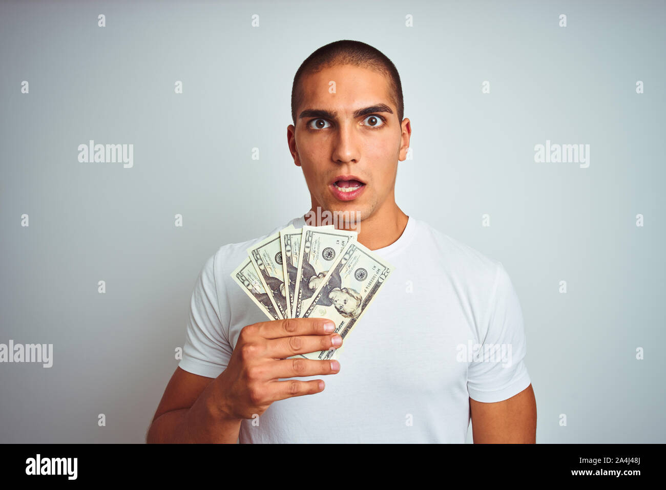 Young handsome man holding dollars over white isolated background ...