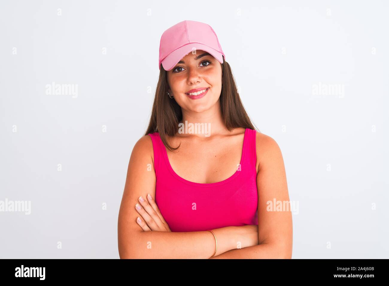 Young beautiful girl wearing pink casual t-shirt and cap over isolated white background happy face smiling with crossed arms looking at the camera. Po Stock Photo