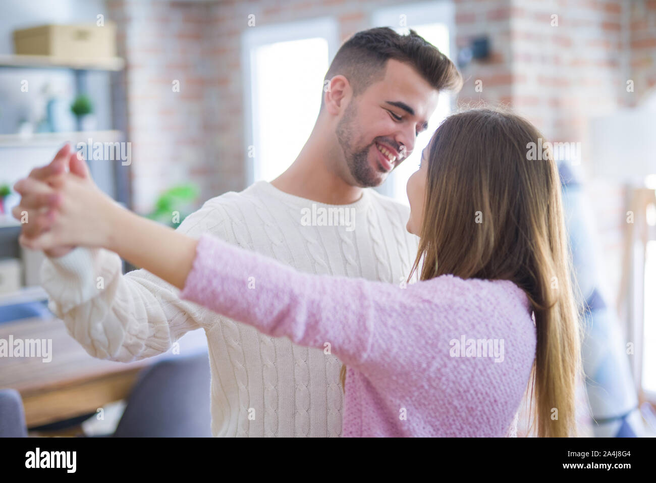 Young beautiful couple in love celebrating dancing moving to a new home ...
