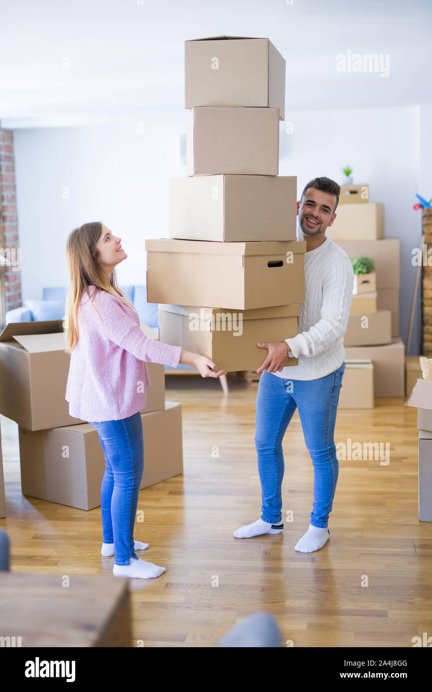 Young couple moving to a new house holding cardboard boxes worried ...