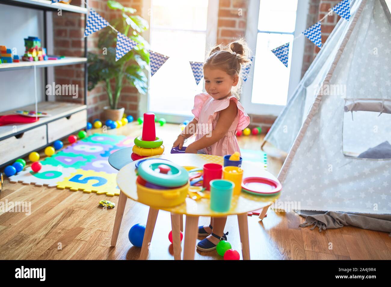 Young beautiful toddler building pyramid using hoops on the table at ...