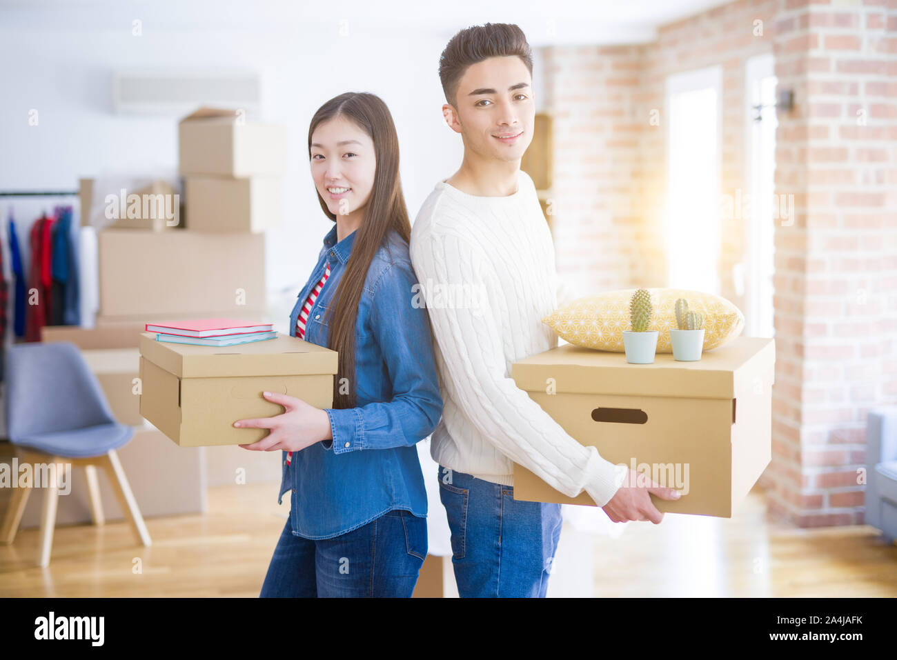 Beautiful young asian couple looking happy holding cardboard boxes ...